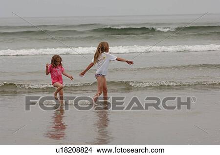 Picture - Two girls playing on ocean beach. Fotosearch