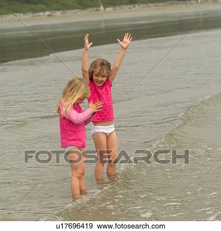 Two girls standing in water on beach View Large Photo Image Stock Photo - Two girls standing in water on beach. Fotosearch