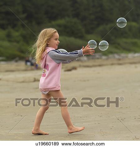 Young girl catching bubbles on beach View Large Photo Image Stock Photo - Young girl catching bubbles on beach. Fotosearch