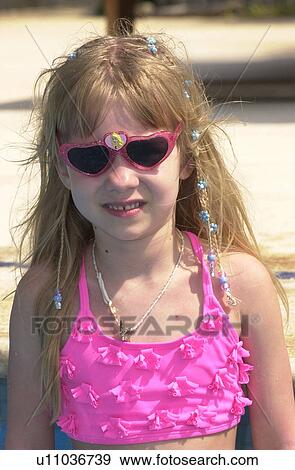 Stock Photo - Young girl in a swimsuit wearing sunglasses looking at camera. Fotosearch