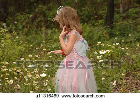 Stock Photo - Young girl in fairy costume picking wildflowers. Fotosearch
