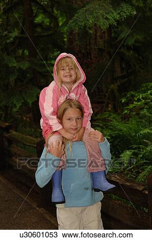 Stock Image - Young girl on shoulders of older child. Fotosearch