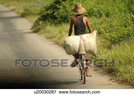 Burmese man riding away on a bike View Large Photo Image Stock Photo - Burmese man riding away on a bike. Fotosearch