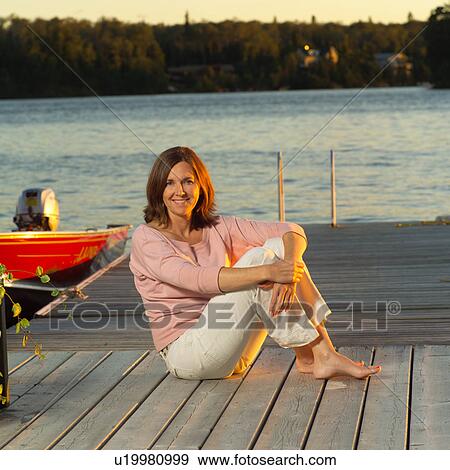 Brunette sitting on dock View Large Photo Image Stock Photo - Brunette sitting on dock. Fotosearch