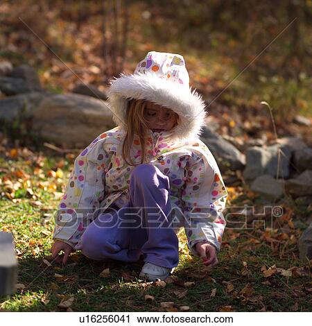 Small child in a hooded jacket picking up a leaf off the ground View Large Photo Image Stock Image - Small child in a hooded jacket picking up a leaf off the ground. Fotosearch
