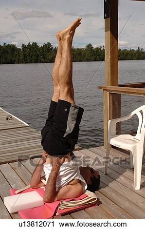 Stock Image - Man in a shoulder pose yoga position. Fotosearch