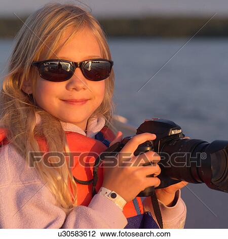 Girl wearing sunglasses and holding a camera View Large Photo Image Stock Image - Girl wearing sunglasses and holding a camera. Fotosearch