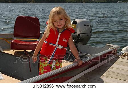 Stock Photograph - Portrait of a young girl wearing a life vest standing in a boat. Fotosearch