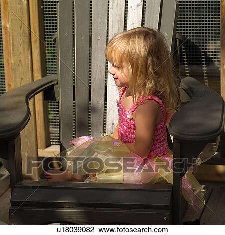Stock Image - Side profile of a young girl sitting in a chair. Fotosearch