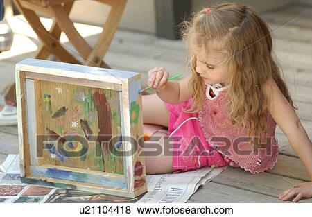 Stock Photo - Young girl sitting and painting. Fotosearch
