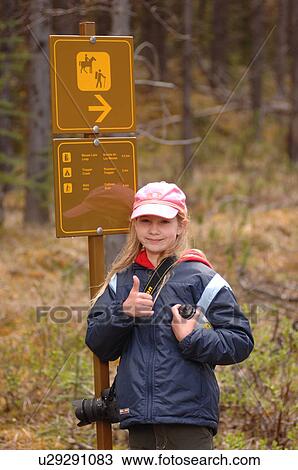 Stock Image - Girl standing by direction sign. Fotosearch