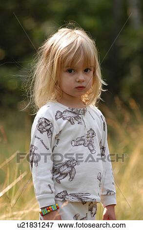 Stock Photo - Portrait of a young girl standing in tall grass. Fotosearch