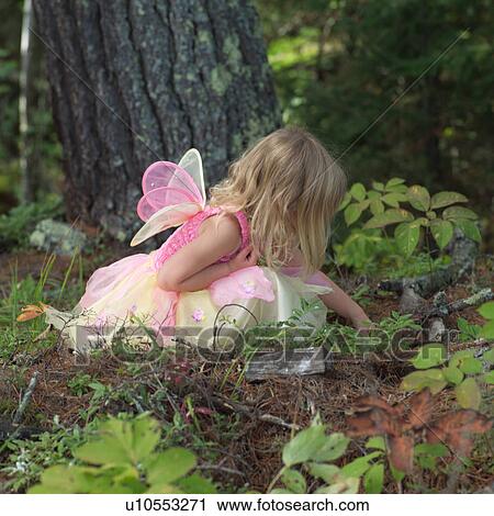 Stock Image - Young girl in a fairy costume sitting in a forest. Fotosearch