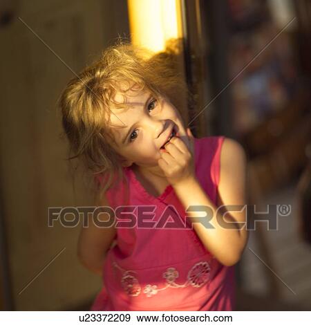 Stock Photo - Young girl leaning against a tree with her fingers in her mouth. Fotosearch