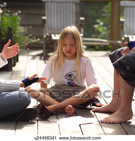 Stock Image - Young girl sitting with friends on a porch. Fotosearch