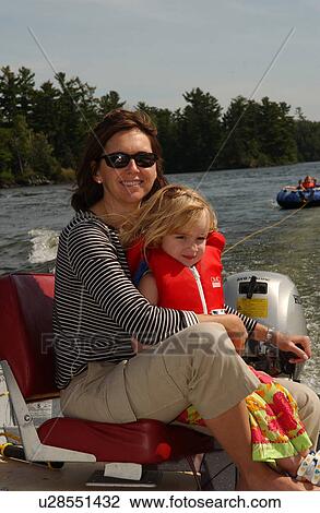 Stock Image - Young woman holding her daughter in a boat. Fotosearch