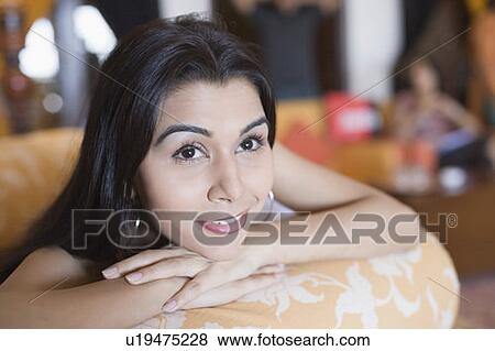 Close-up of a young woman resting her chin on her hands and smiling View Large Photo Image Stock Photo - Close-up of a young woman resting her chin on her hands and smiling. Fotosearch