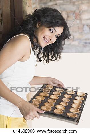 Portrait of a young woman holding a tray of biscuits and smiling View Large Photo Image Stock Image - Portrait of a young woman holding a tray of biscuits and smiling. Fotosearch