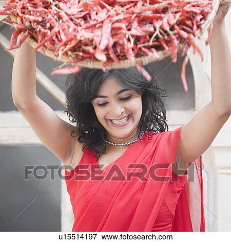 Stock Photo - Young woman spraying red chili peppers from a basket. Fotosearch