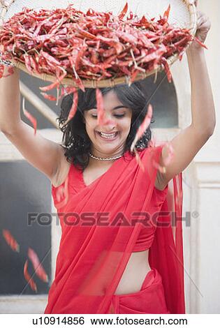 Stock Photograph - Young woman spraying red chili peppers from a tray. Fotosearch