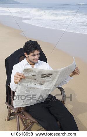 Businessman sitting in an armchair and reading a newspaper on the beach View Large Photo Image Stock Photo - Businessman sitting in an armchair and reading a newspaper on the beach. Fotosearch