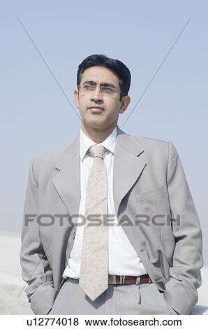 Stock Photo - Close-up of a businessman standing with his hands in his pockets. Fotosearch