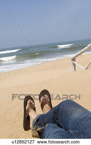 Low section view of a man lying on the beach View Large Photo Image Stock Photo - Low section view of a man lying on the beach. Fotosearch