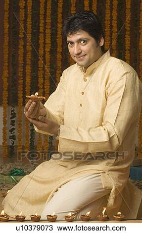 Stock Image - Mid adult man lighting an oil lamp. Fotosearch
