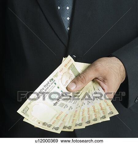 Stock Photo - Mid section view of a businessman holding Indian five hundred rupee notes. Fotosearch