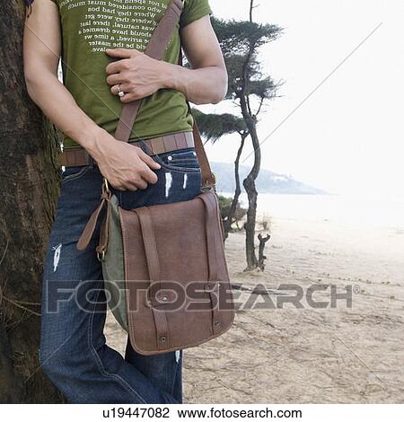 Mid section view of a man leaning against a tree on the beach View Large Photo Image Stock Image - Mid section view of a man leaning against a tree on the beach. Fotosearch