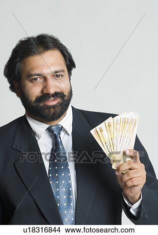 Picture - Portrait of a businessman holding Indian five hundred rupee notes. Fotosearch