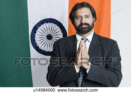 Stock Image - Portrait of a businessman standing in front of an Indian flag. Fotosearch