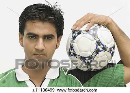 Portrait of a young man carrying a soccer ball on his shoulder View Large Photo Image Stock Photo - Portrait of a young man carrying a soccer ball on his shoulder. Fotosearch