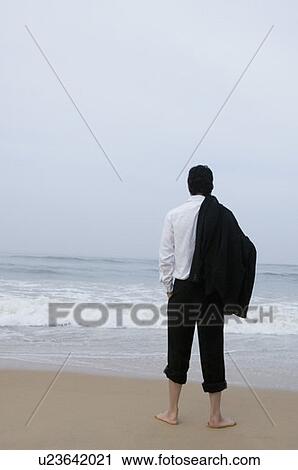 Rear view of a businessman standing on the beach View Large Photo Image Stock Image - Rear view of a businessman standing on the beach. Fotosearch