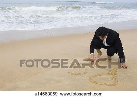 Stock Photo - Young man drawing Rs on the beach. Fotosearch