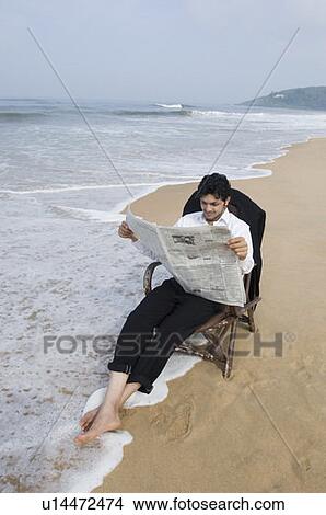 Young man reading a newspaper on the beach View Large Photo Image Picture - Young man reading a newspaper on the beach. Fotosearch