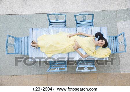 Stock Photo - High angle view of a young woman lying on a table. Fotosearch