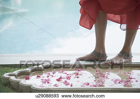 Stock Image - Low section view of a woman standing at the poolside. Fotosearch