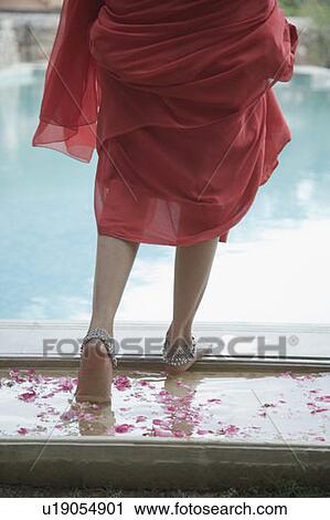 Stock Image - Low section view of a woman walking towards a swimming pool. Fotosearch