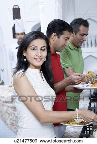 Stock Photo - Mid adult woman with her friends having lunch. Fotosearch