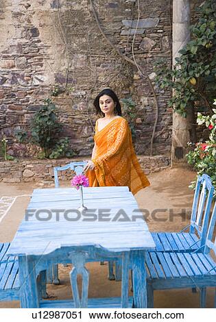 Stock Image - Portrait of a mid adult woman standing near a dining table. Fotosearch