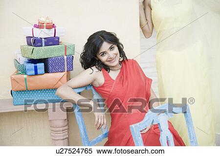 Portrait of a young woman sitting on a chair with gifts beside her View Large Photo Image Stock Photography - Portrait of a young woman sitting on a chair with gifts beside her. Fotosearch