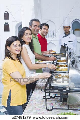 Stock Photo - Portrait of two mid adult couples having lunch with a chef standing in the background. Fotosearch
