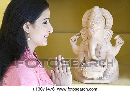 Side profile of a mid adult woman praying in front of a statue of God Ganesha View Large Photo Image Stock Photograph - Side profile of a mid adult woman praying in front of a statue of God Ganesha. Fotosearch