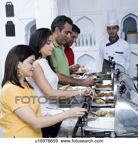 Stock Photo - Side profile of two mid adult couples having food in a party. Fotosearch