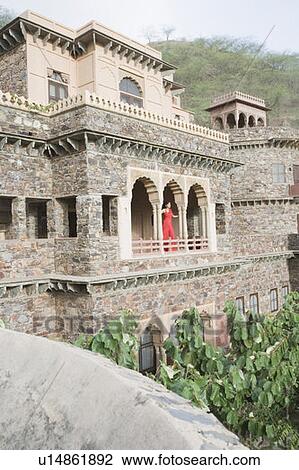Stock Image - Young woman standing at the balcony of a palace, Neemrana Fort Palace, Neemrana, Alwar, Rajasthan, India. Fotosearch