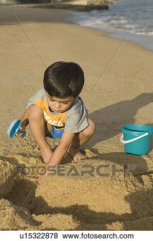 Stock Photo - Boy making a sand castle on the beach. Fotosearch