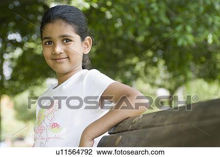 Girl leaning against a bench and smirking View Large Photo Image Stock Image - Girl leaning against a bench and smirking. Fotosearch