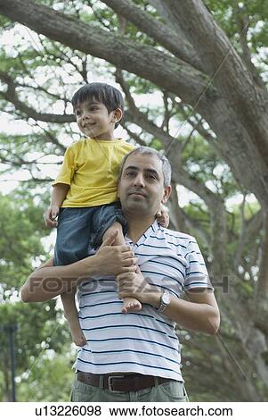 Low angle view of a mid adult man carrying his son on his shoulders View Large Photo Image Stock Photo - Low angle view of a mid adult man carrying his son on his shoulders . Fotosearch