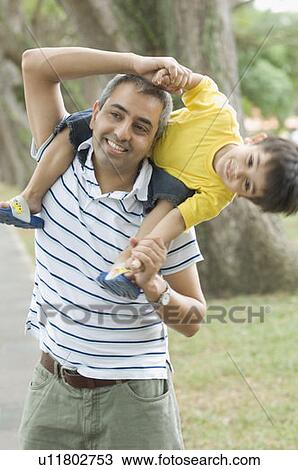 Mid adult man carrying his son on his shoulder View Large Photo Image Stock Image - Mid adult man carrying his son on his shoulder. Fotosearch